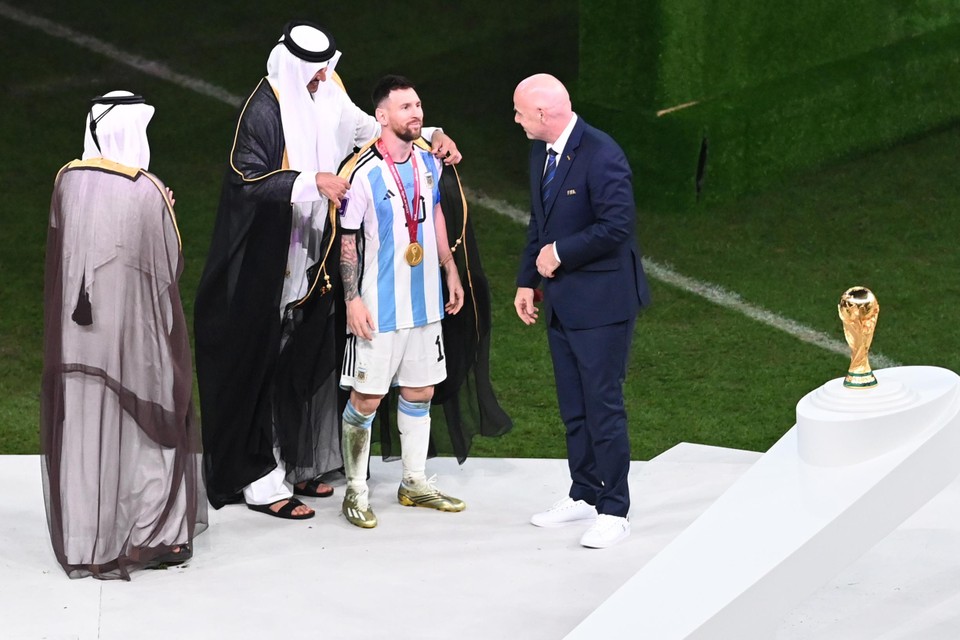 Lionel Messi wordt door de emir van Qatar in een bisht, een lokaal gewaad, gehuld voordat hij de wereldbeker mag tonen aan het publiek.