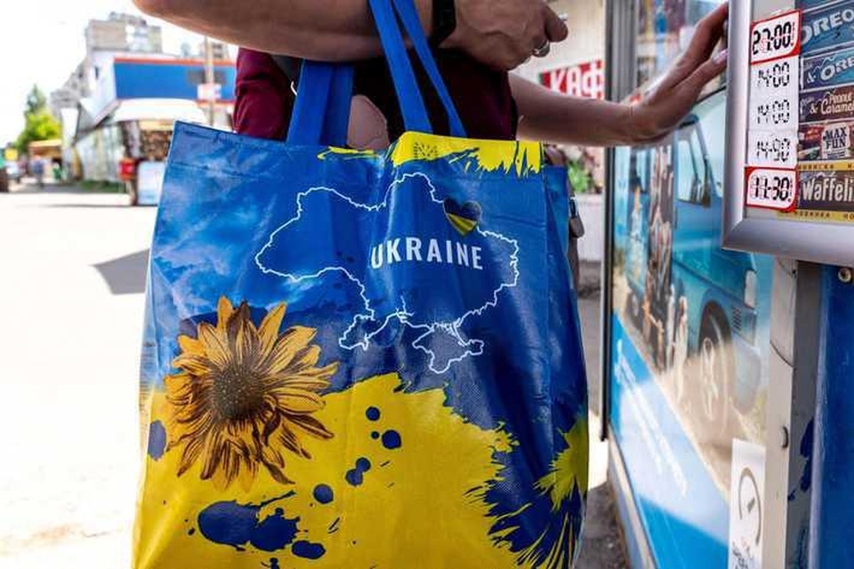 Een vrouw met een tas donderdag in het centrum van Kiev. In de hoofdstad prijken nadrukkelijk de nationale kleuren geel en blauw op reclameborden, kleding en andere producten. 
