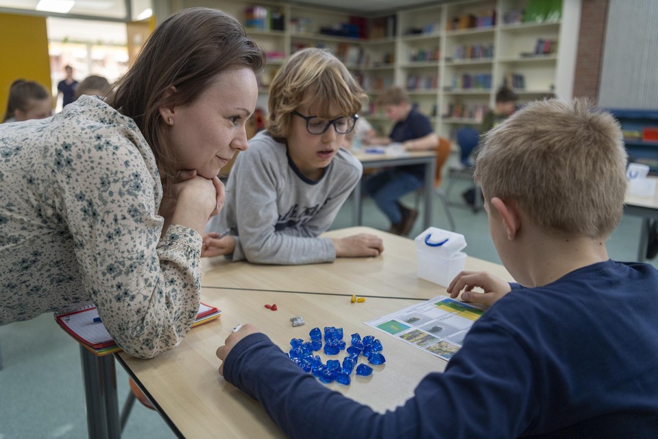 Monique Junggeburt kijkt samen met leerlingen van basisschool à Hermkes hoeveel gekleurde steentjes tussen de blauwe zitten. 