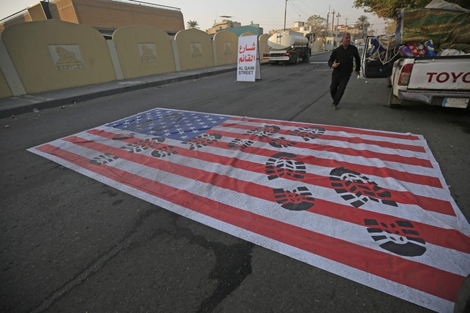 Een Amerikaanse vlag is op straat geschilderd zodat auto’s eroverheen kunnen rijden. Westerse regeringen vrezen voor represailles na de dood van de Iraanse generaal Soleimani. 