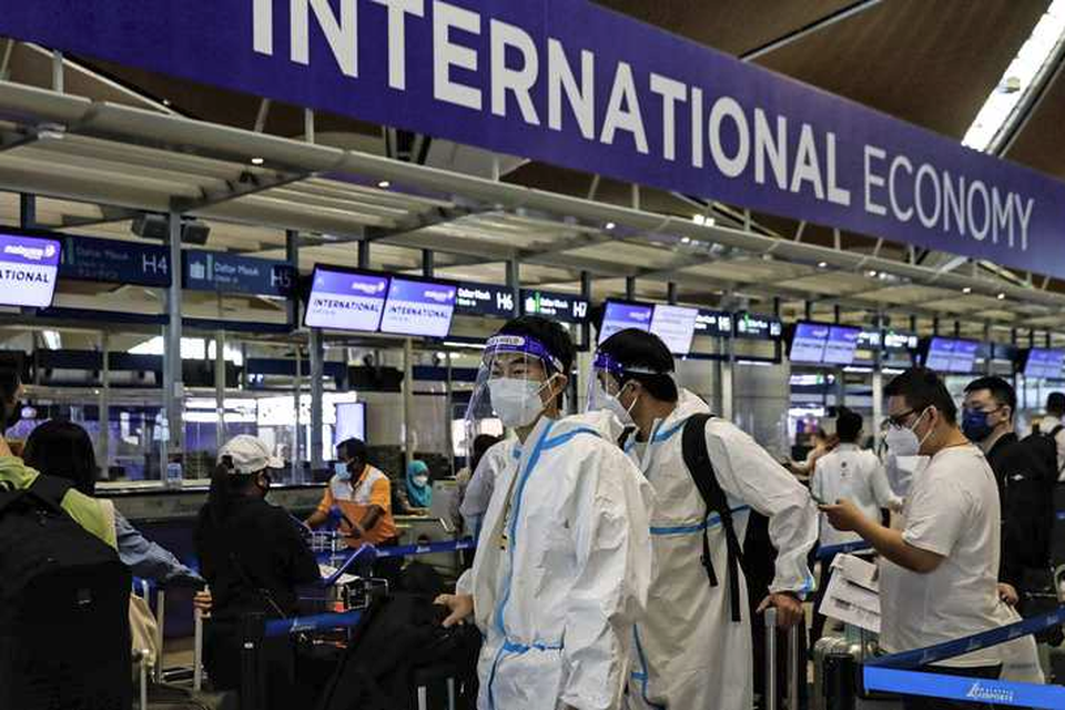 Passagiers gehuld in beschermende kledij staan op het vliegveld van Kuala Lumpur te wachten op groen licht om verder te mogen vliegen nu veel landen extra restricties hebben opgelegd aan binnenkomende buitenlandse vluchten. 