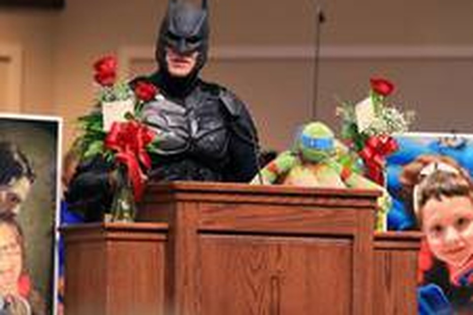 Batman houdt een woordje voor bezoekers van de begrafenis van de overleden Jacob Hall.