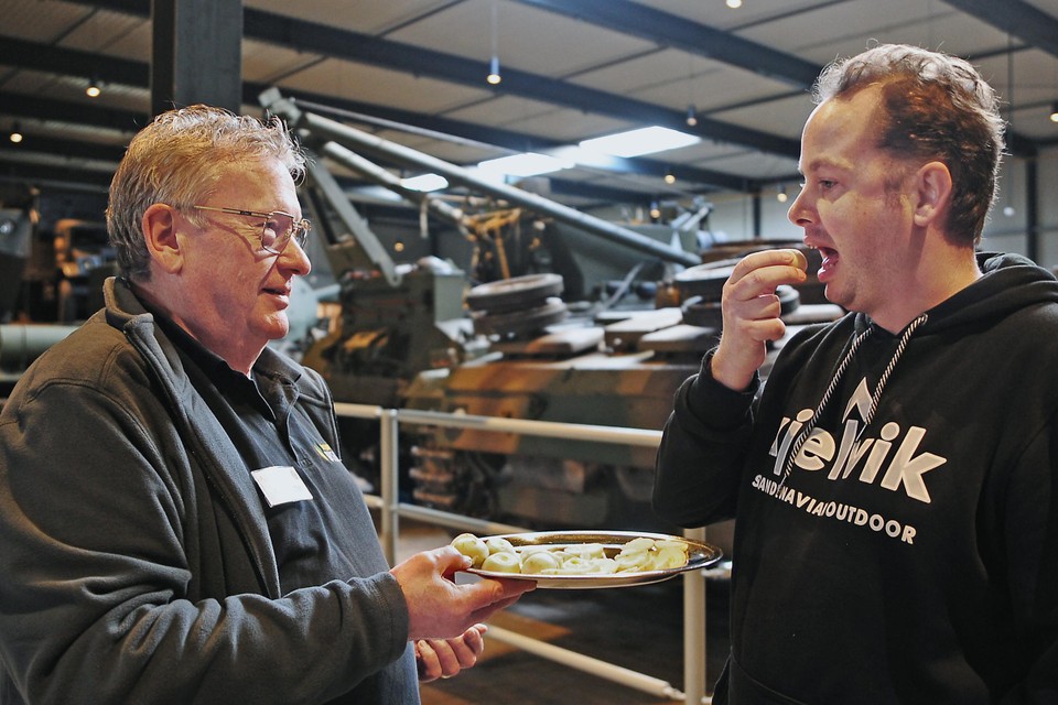 Museumvrijwilliger Ger Hutten (links) laat bezoeker Dieter de Jong (rechts) een tulpenbolletje proeven.