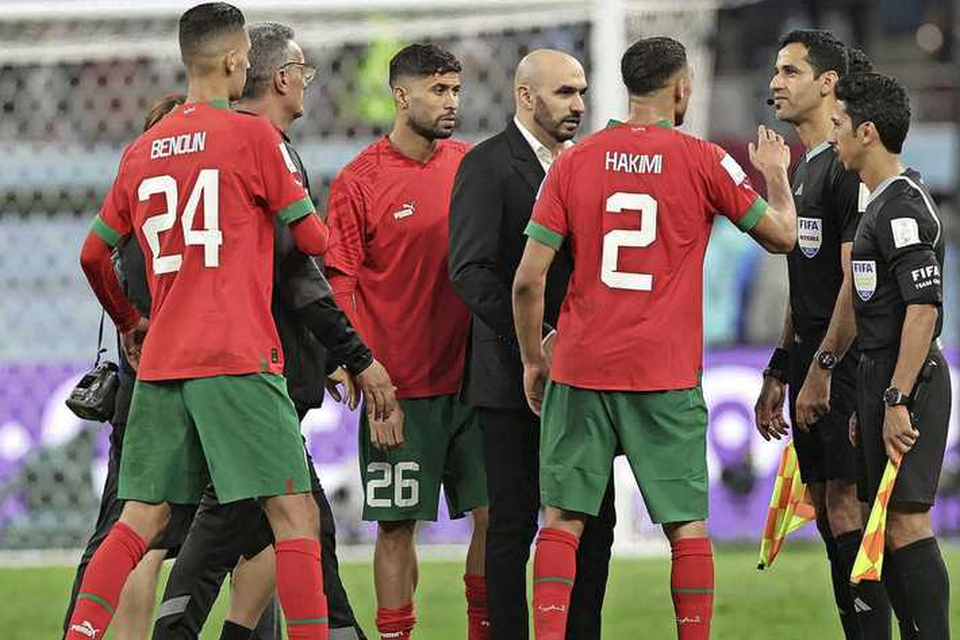 Achraf Hakimi haalt verhaal bij scheidsrechter Abdulrahman Al Jassim. Bondscoach Walid Regragui (m) staat er ook bij.