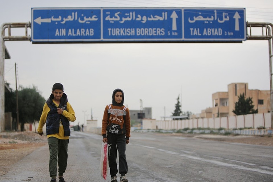 Syrische jongens lopen over een verlaten weg die naar de grensstad Tal Abyad leidt. 