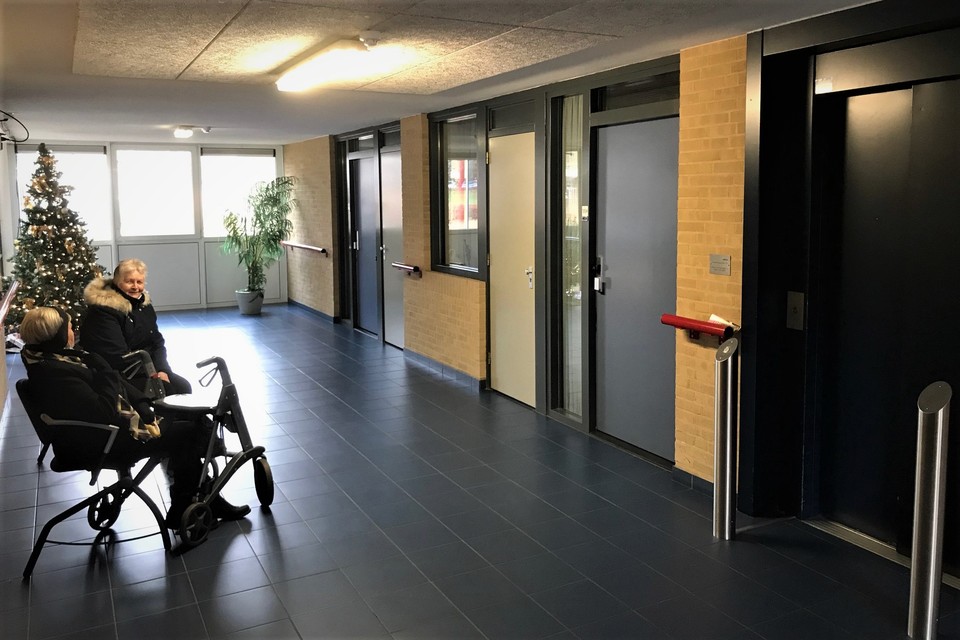 Een bewoonster en haar bezoek wachten in de hal van De Corisberg. Rechts de lift, die in en buiten het woon/zorgcomplex tot veel gespreksstof leidt. 