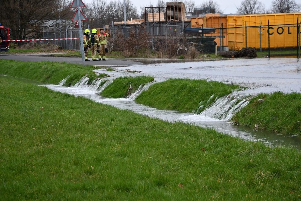 Het water stroomt vanaf het terrein van de Gasunie over de weg naar een sloot.