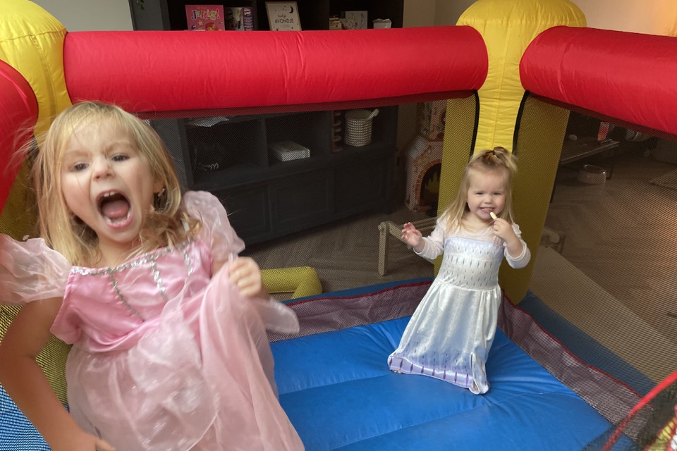Isa (links) en Lis in hun prinsessenjurk op het springkussen in de woonkamer. 