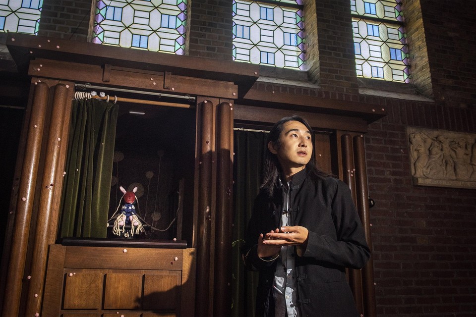 Hussel Zhu voor een van zijn werken. De bolletjes op de biechtkamer symboliseren de ‘ziektes’ van de katholieke kerk. 