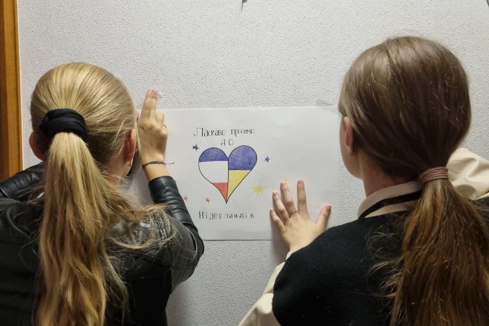 Leerlingen hangen hun eigen tekeningen op in Huize de Berg voor Oekraïense vluchtelingen: „Hartelijk welkom in Nederland”. 