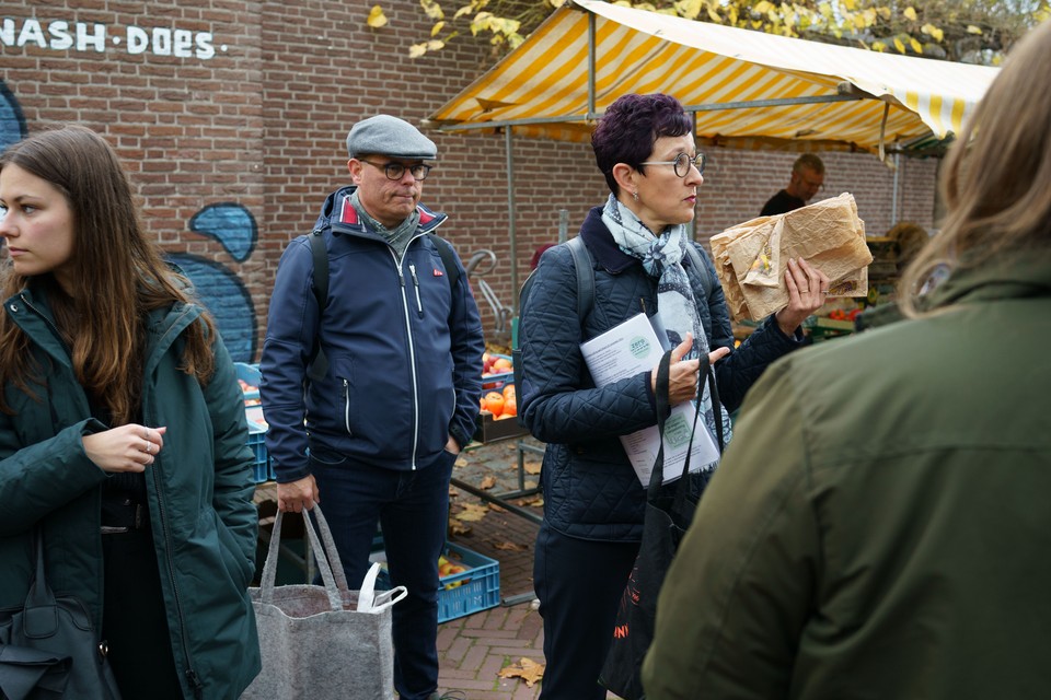 Vera Hoeksma met papieren zakken die hergebruikt kunnen worden om opnieuw groente en fruit mee te nemen. Links haar man Marco en dochter Laura.   