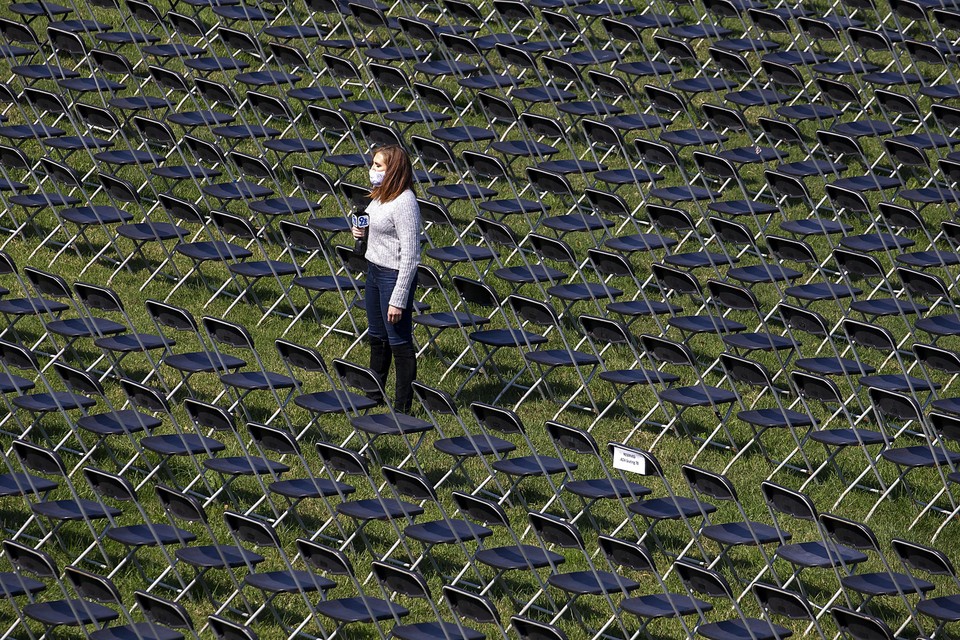 Oktober 2020: een vrouw staat in Washington DC tussen lege stoelen ter herinnering aan de tot dan 200.000 coronadoden in de VS. 