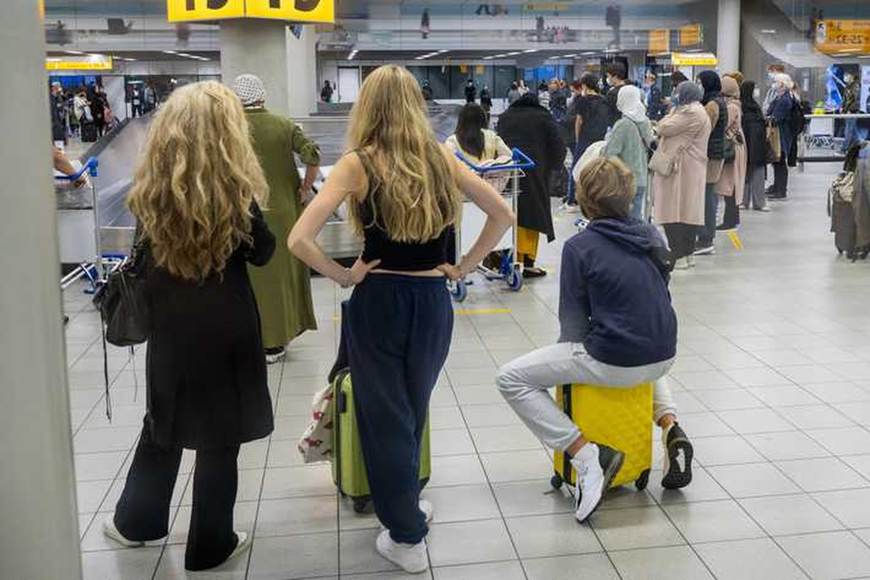 Reizigers worden opgewacht in de ontvangsthal op luchthaven Schiphol. 