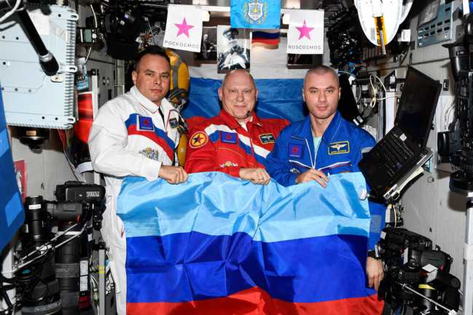 (Vlnr) Sergei Korsakov, Oleg Artemyev en Denis Matveev poseren met een vlag van de zelfverklaarde Volksrepubliek Loehansk 