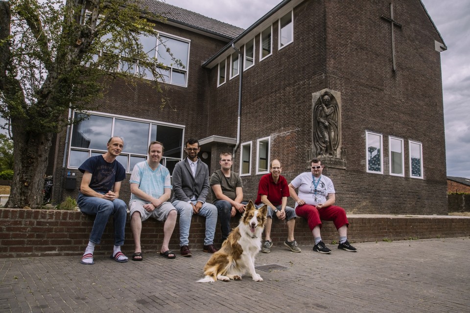 Zes van de tien mannen die begeleid wonen in de oude jongensschool in Heugem, met hond Luna. 