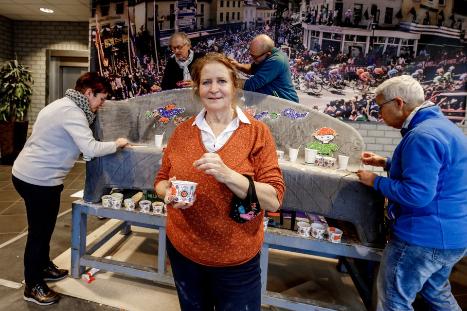 Marij van Aken. Achter haar beplakken vrijwilligers de social sofa met stukjes gekleurd glas. 